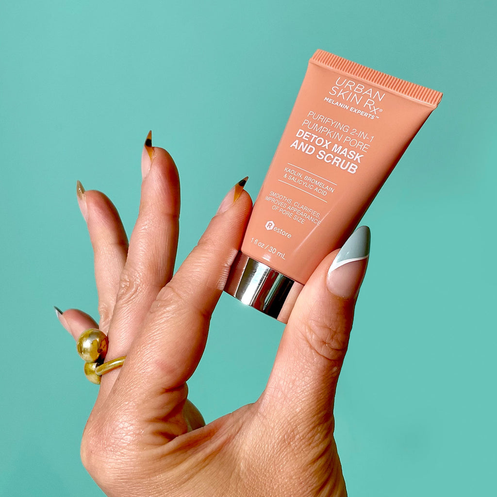 Hand holding a tube of Urban Skin Rx travel size Purifying 2-in-1 Pumpkin Mask and Scrub.
