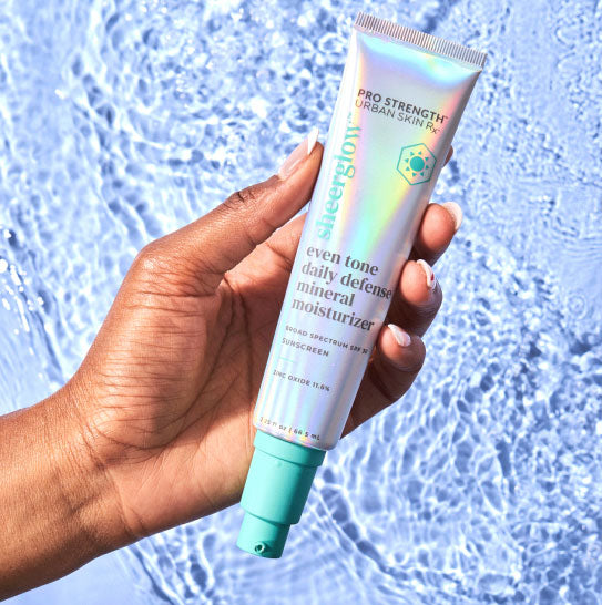 Woman holding bottle of Urban Skin Rx Even Tone Daily Defense Mineral Moisturizer