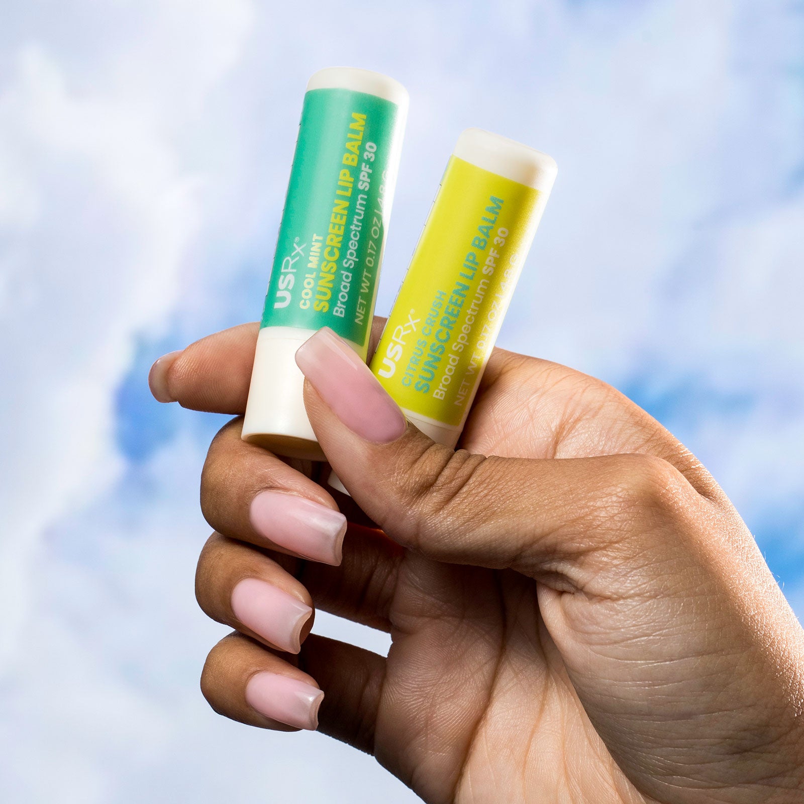 Woman holding 2 USRX Sunscreen Lip Balms in her hand