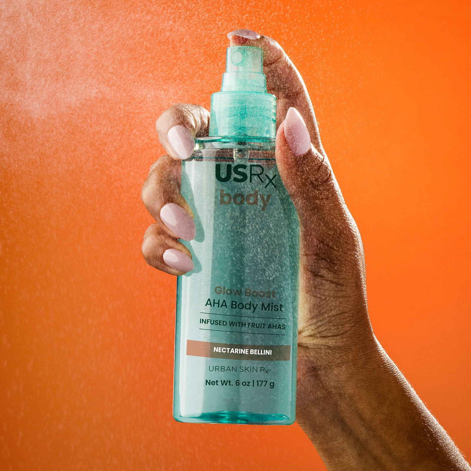 Woman spraying USRX Glow Boost AHA Body Mist in Nectarine Bellini