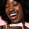 Smiling woman holding a tube of USRx Tinted Hydrating Lip Treatment in Toasty