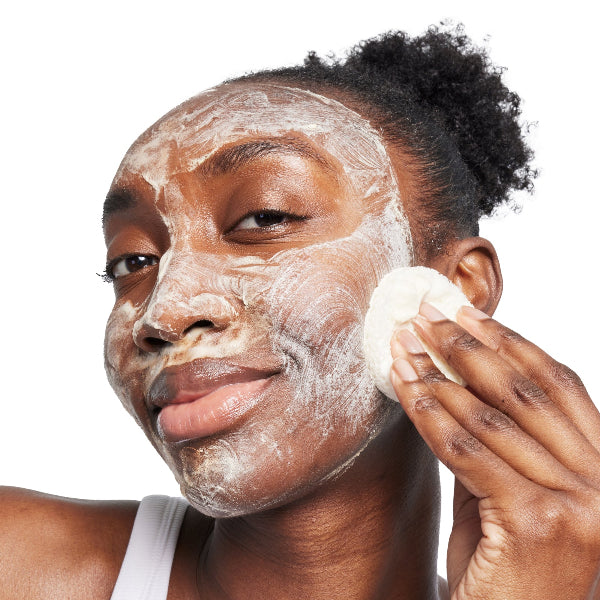 Woman applying a facial cleanser with a white background