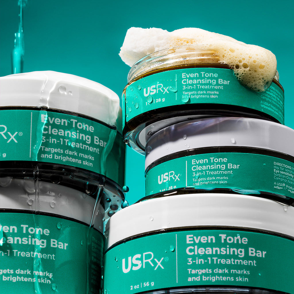 Multiple jars of USRx Even Tone Cleansing Bar, with lather shown coming out of open jar