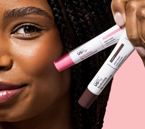 Woman holding 2 tubes of USRx Hydrating lip treatment near her face