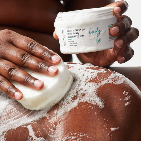 Woman applying USRx Clear and Even Tone Body Cleansing Bar to her skin