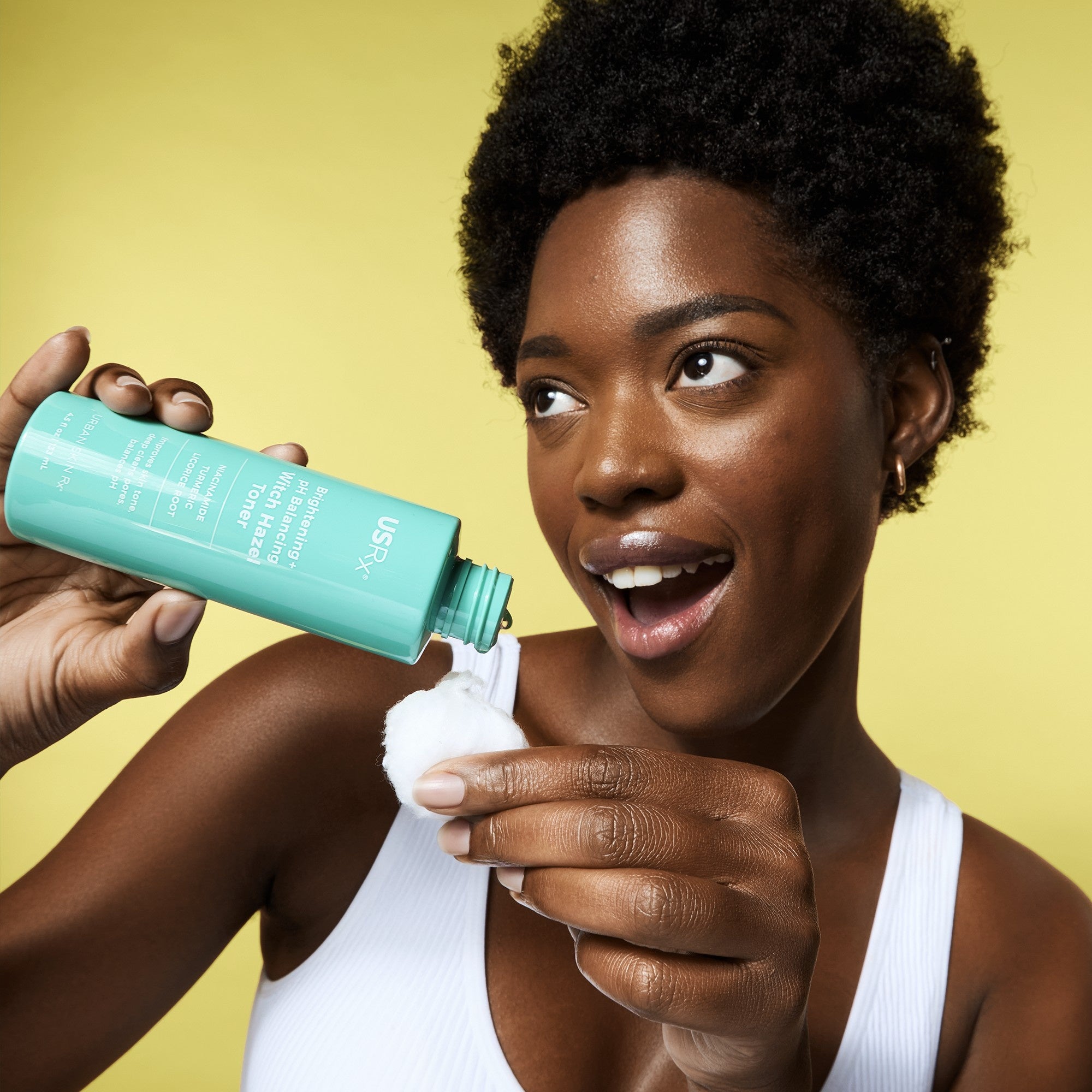 Woman dispensing USRx Witch Hazel Toner onto a cotton ball